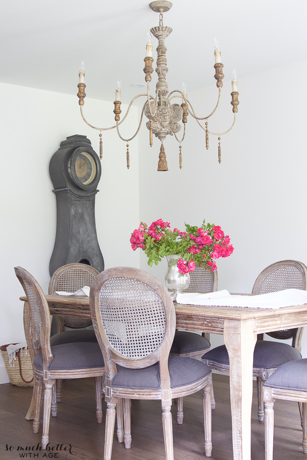 A wooden dining room table with dark pink flowers on it.