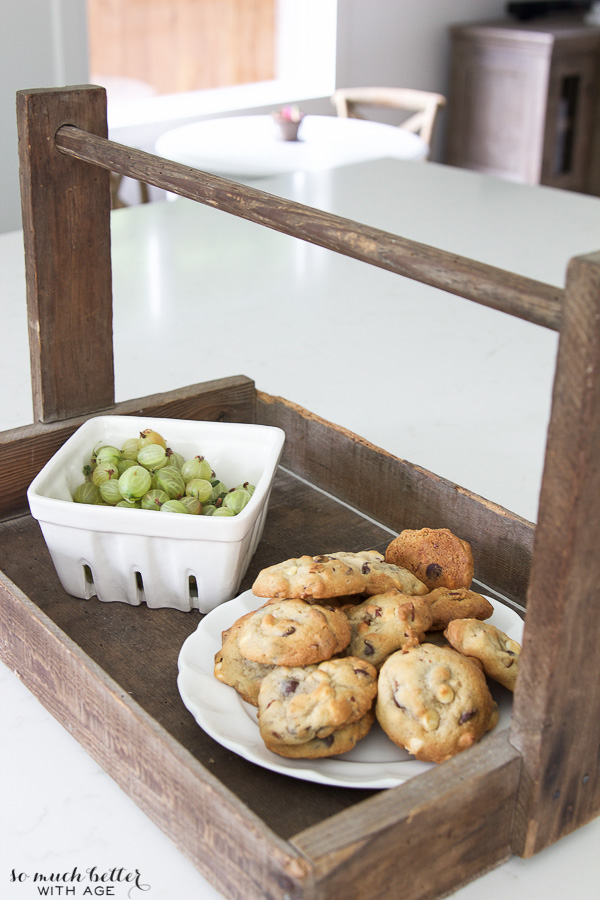 A wooden serving tray with cookies and grapes.