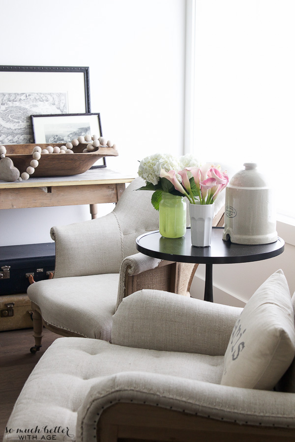 Two neutral armchairs flank a round table in the living room.