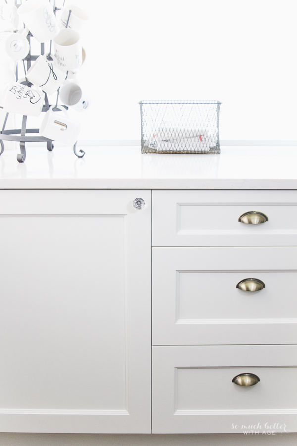 The white kitchen cabinets under the sink plus the drawers with the brushed brass pulls.
