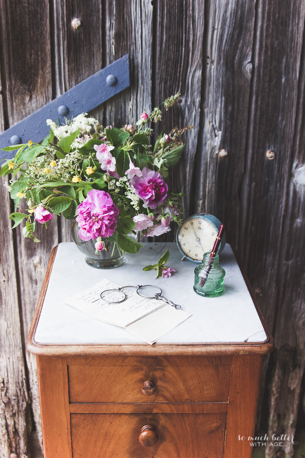 There are flowers on a wooden cabinet beside a cloth and pen in a well.