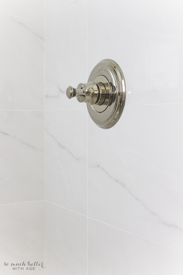  Delta polished nickel shower faucet with porcelain tile.