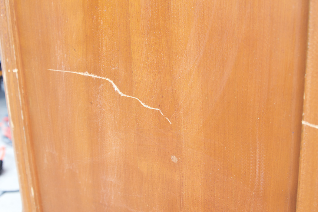 Big dent or mark in side of wooden piece of furniture. 