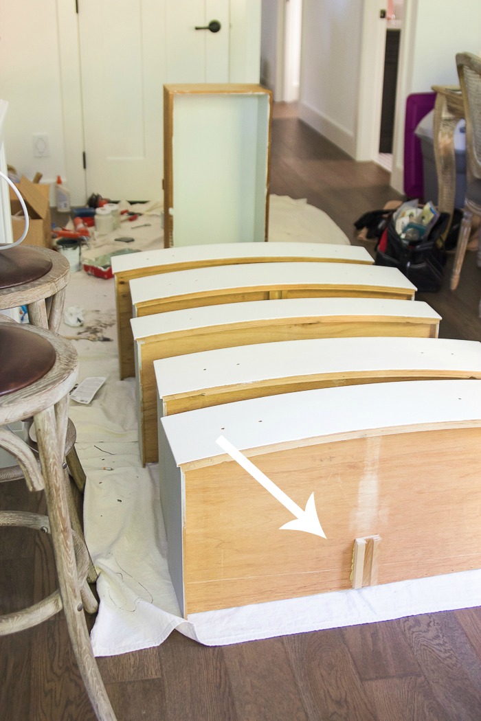 Bottoms of drawers lined up on floor with arrow pointing to a guide rail. 