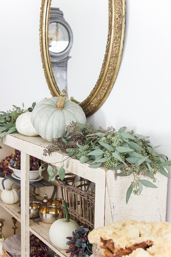 A beautiful set of pumpkins and seeded eucalyptus on the mantle.