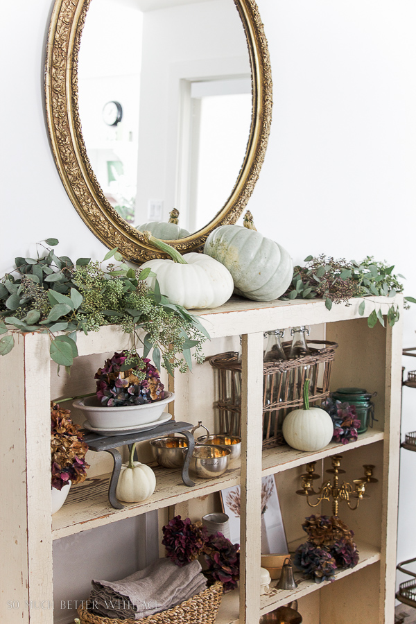 A large gold mirror is above the wooden shelf.