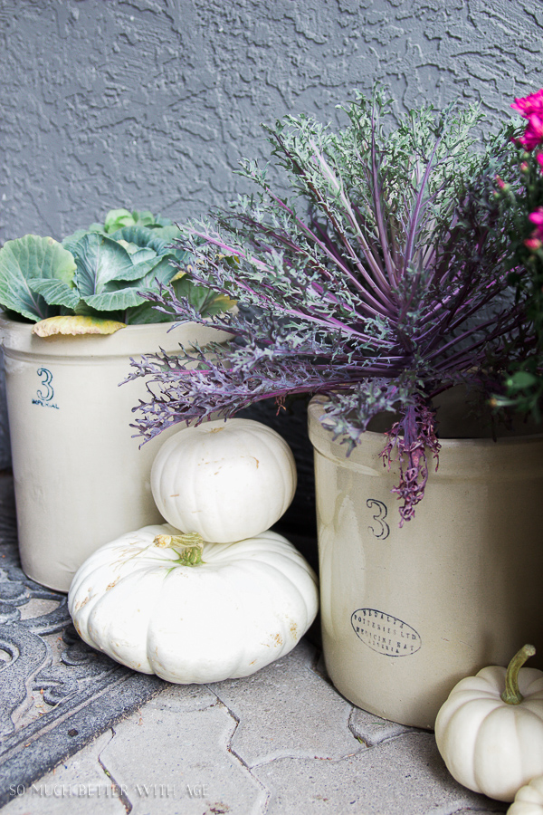 There are crocks beside the white pumpkins.