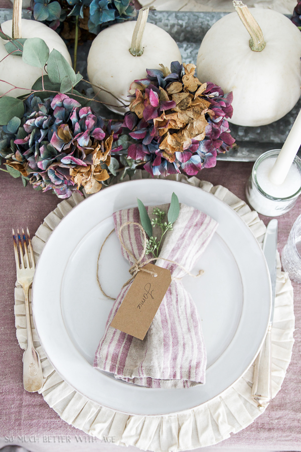 A pink an white napkin wrapped in twine with some seeded eucalyptus.