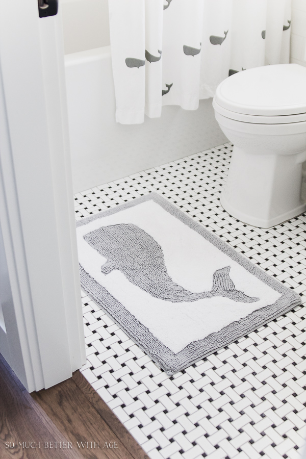 A clean and white bathroom with a whale rug.