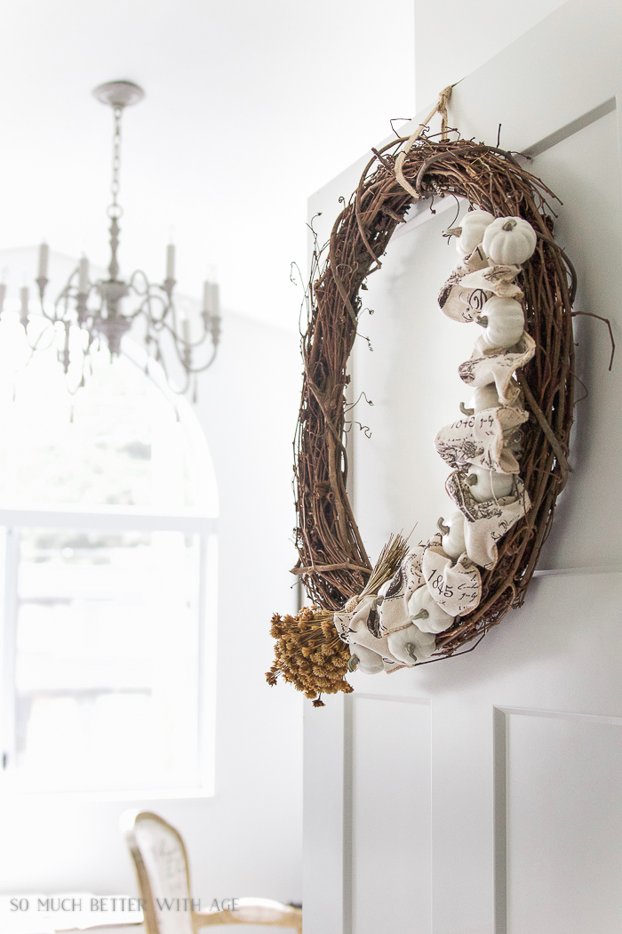 Pumpkins and ribbon wreath hanging on the door in house.