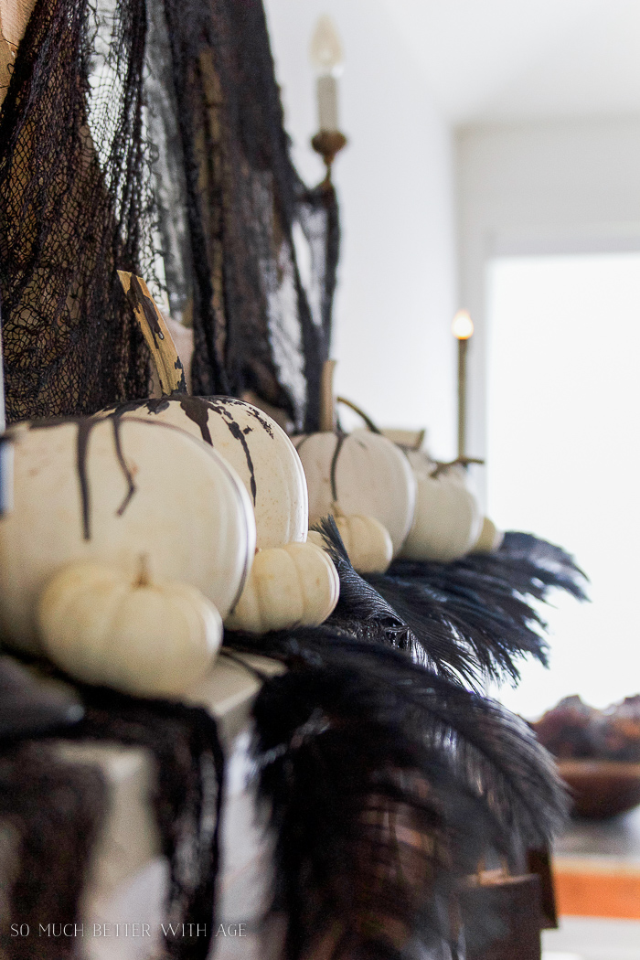 White pumpkins with black wax drippings on them.