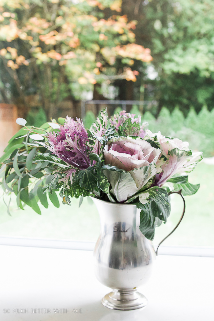 A beautiful silver pitcher with kale flowers.