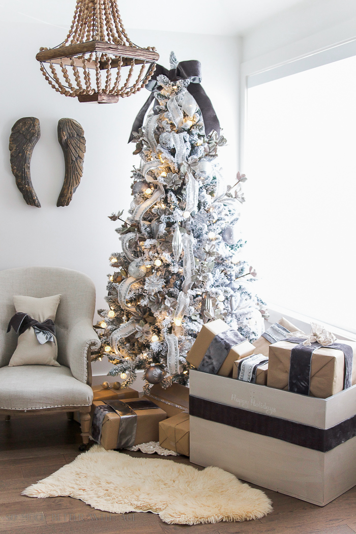 A white fur rug in front of the painted trunk and Christmas tree.