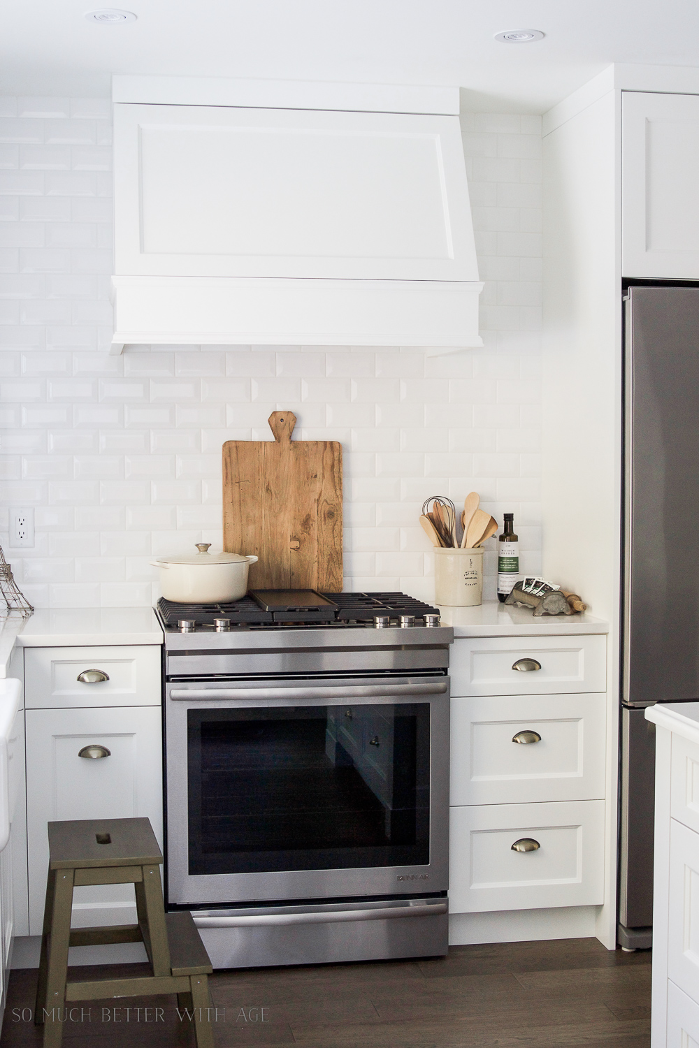  The renovated kitchen after picture of white cabinets and stainless steel appliances.