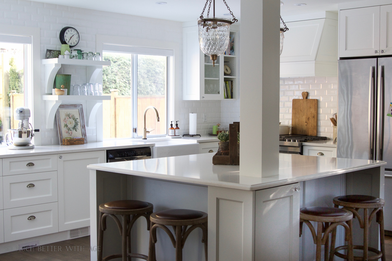 A white kitchen island, with pendant lights and wooden stools.
