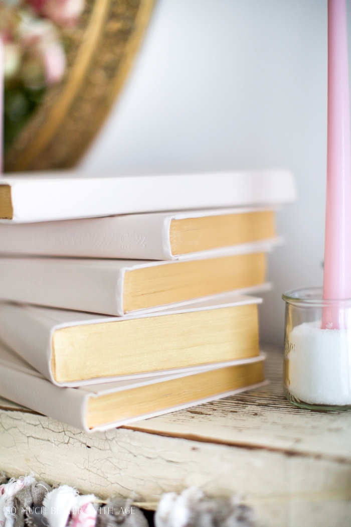 There is a pink candle beside the old books.