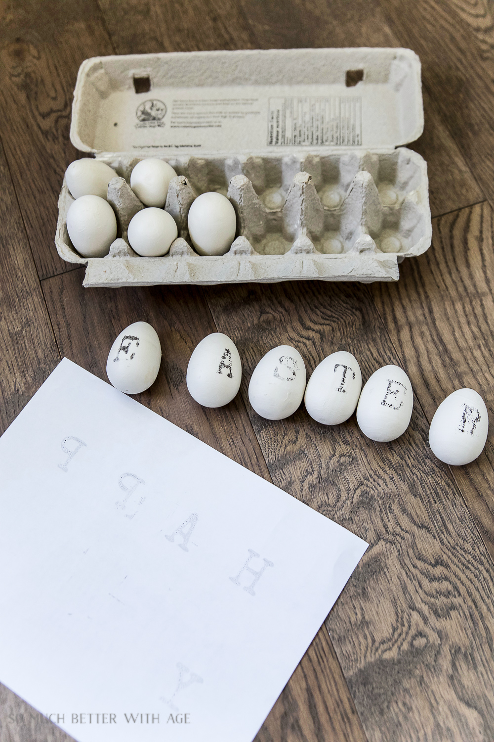 Eggs in a carton and some eggs on the table with inked letters on them.