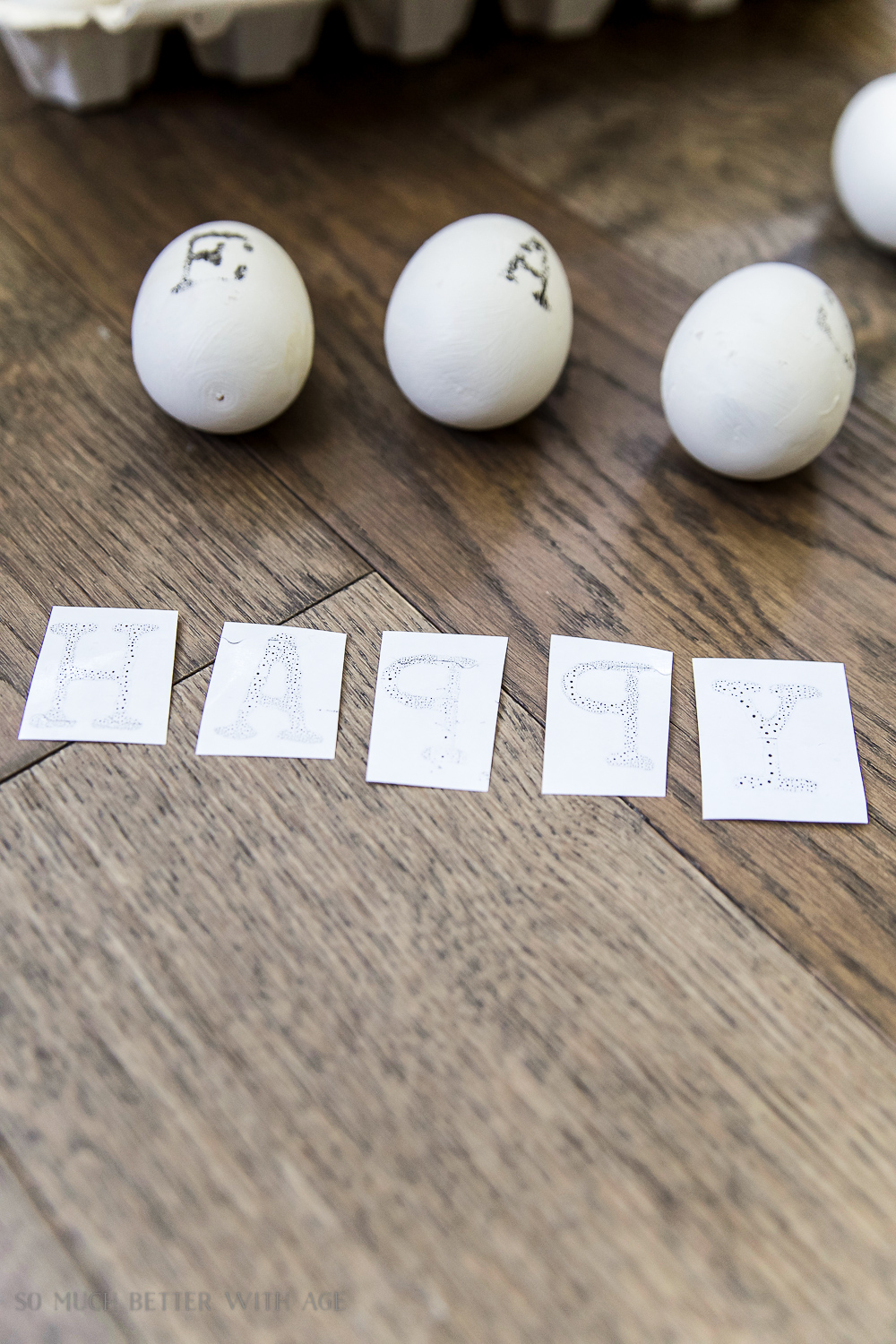 The words Happy in ink spelled out on individual white sheets of transfer paper.