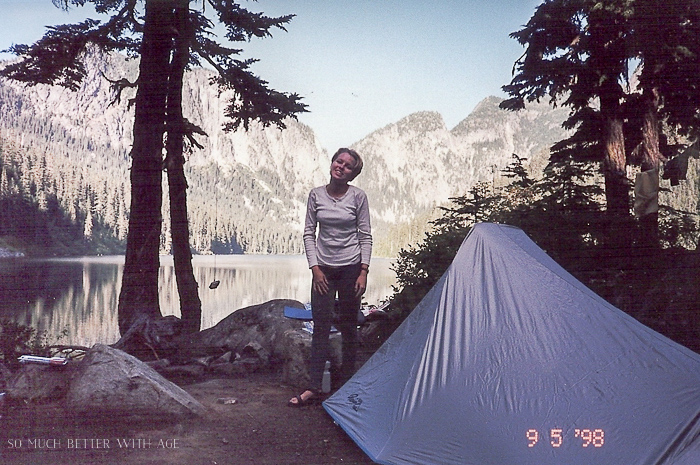 Setting up a tent my the lake with mountains in the distance.