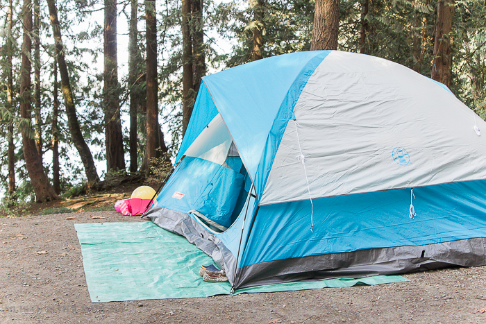 White and blue tent set up by lake.