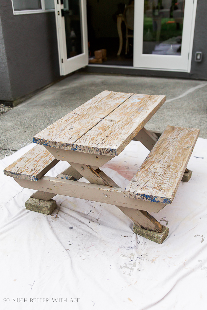 An unpainted picnic table on the patio.