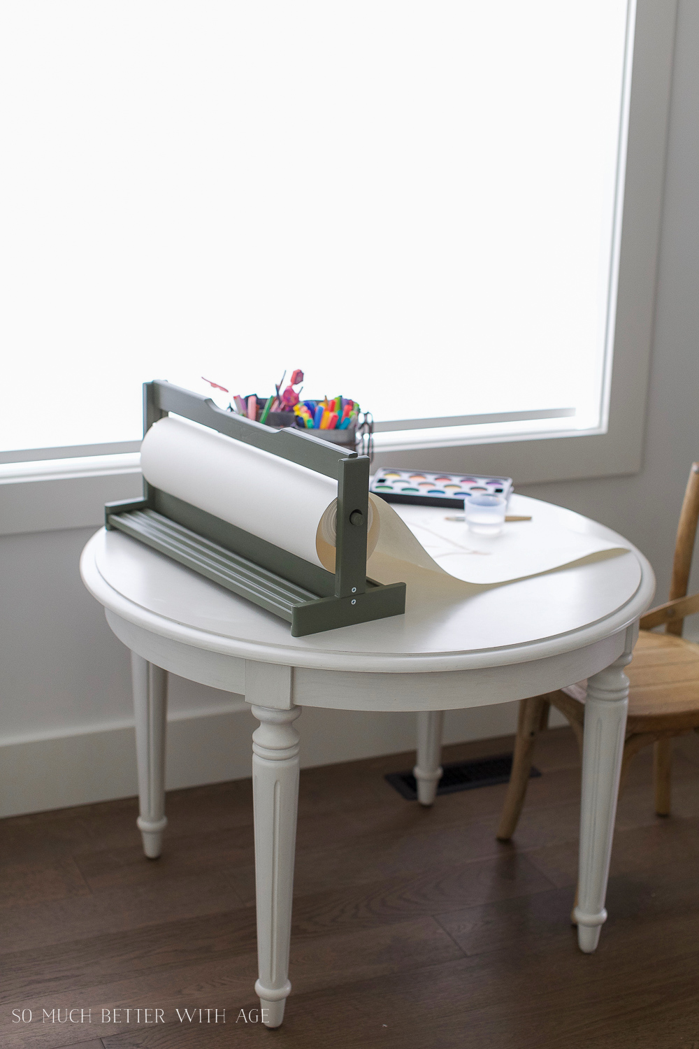 An Ikea table with paper, pens and paint on it.