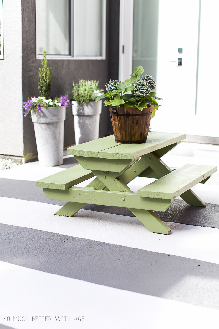 A kids picnic table with a bucket of flowers on it.