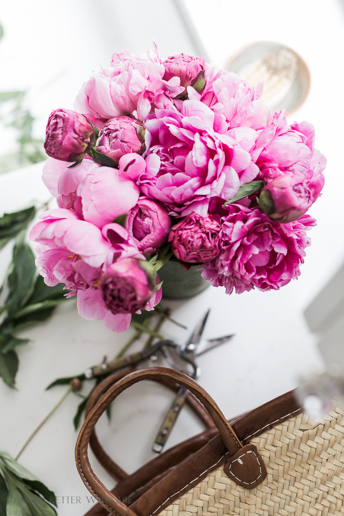 Purple peony flowers on a counter with a handbag.