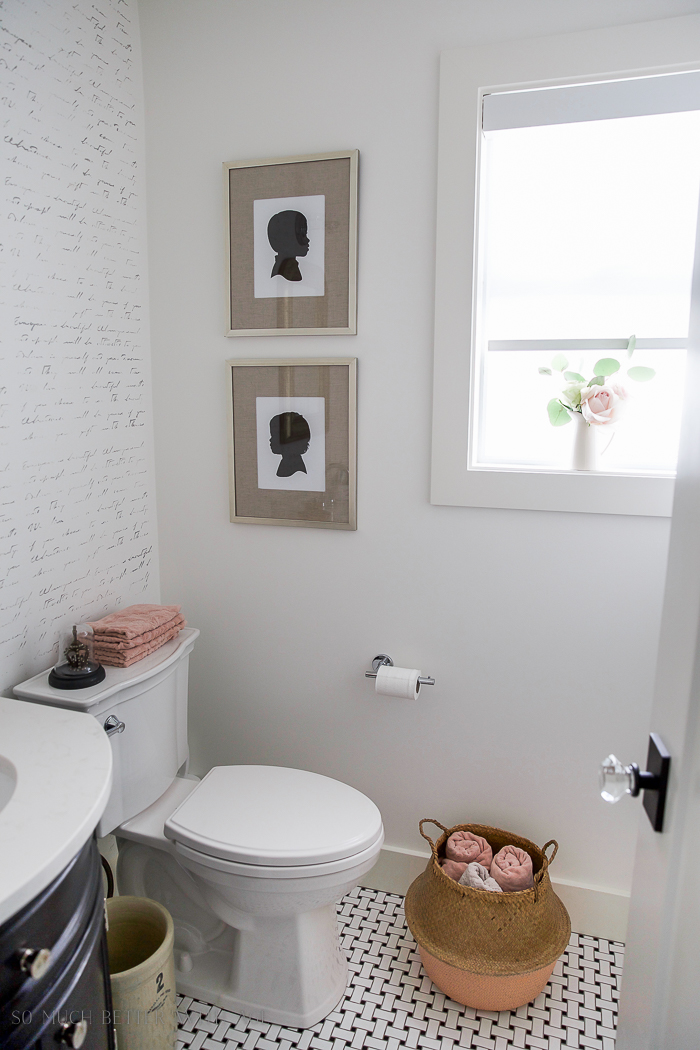 There is a stenciled wall in the bathroom and a basket filled with towels.