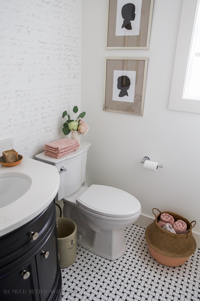 Pink towels are folded and on the top of the toilet.