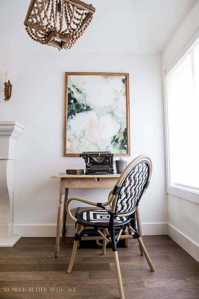 The bistro chair at a wooden desk with an antique typewriter.