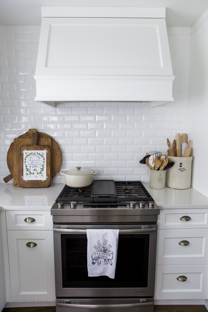 White kitchen with French bread boards or cutting boards leaning against subway tile backsplash.
