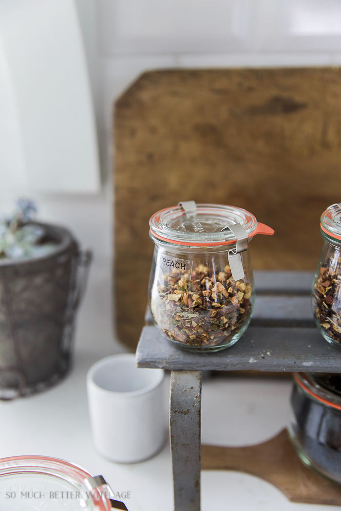 A glass container with loose tea inside it and a label that says peach.