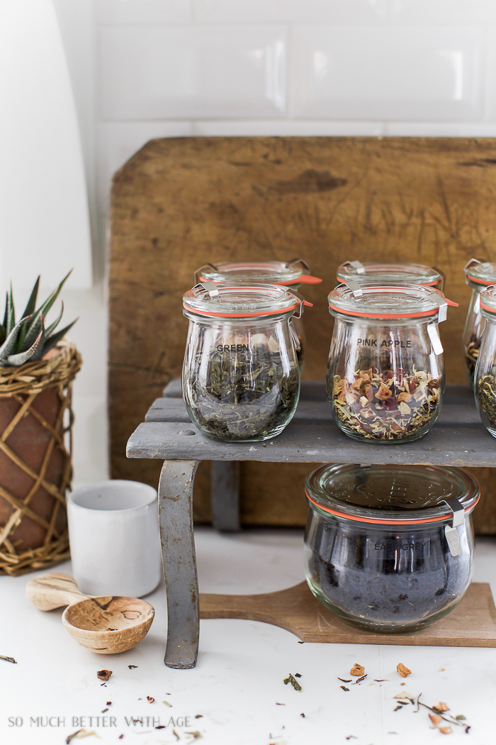 Glass jars filled with tea on the white counter.