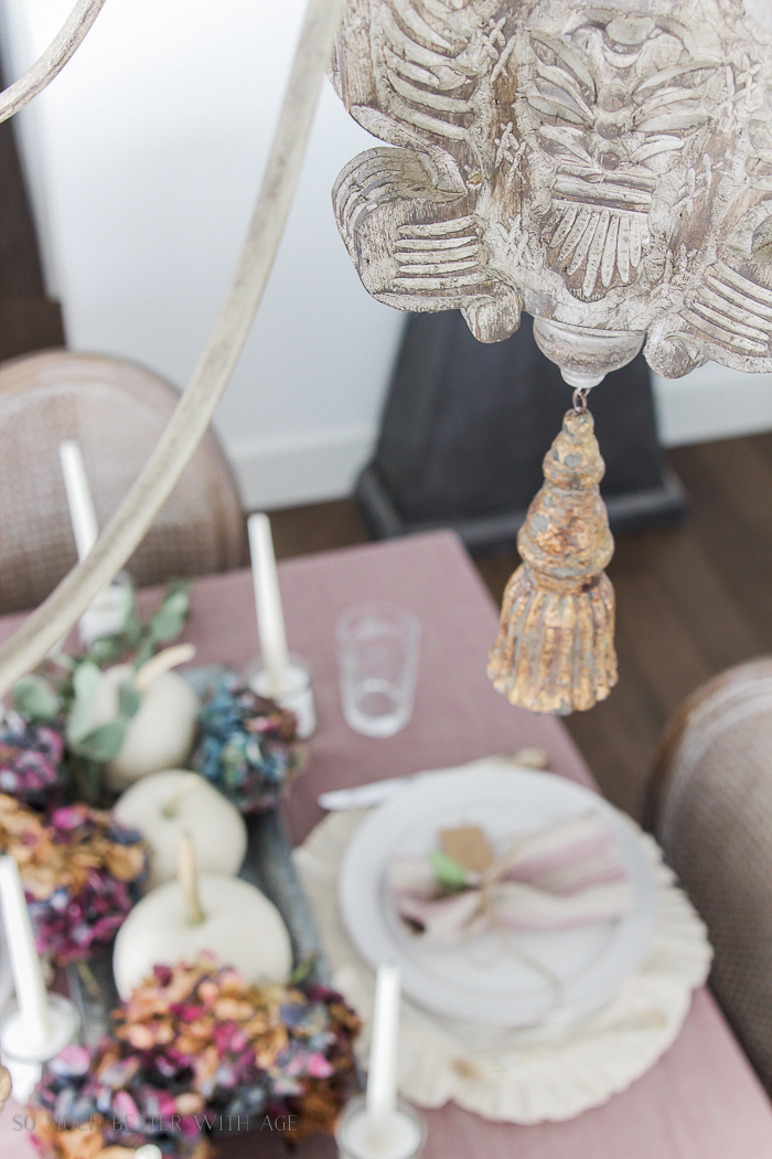 Table set for the holidays with wooden chandelier hanging over top.