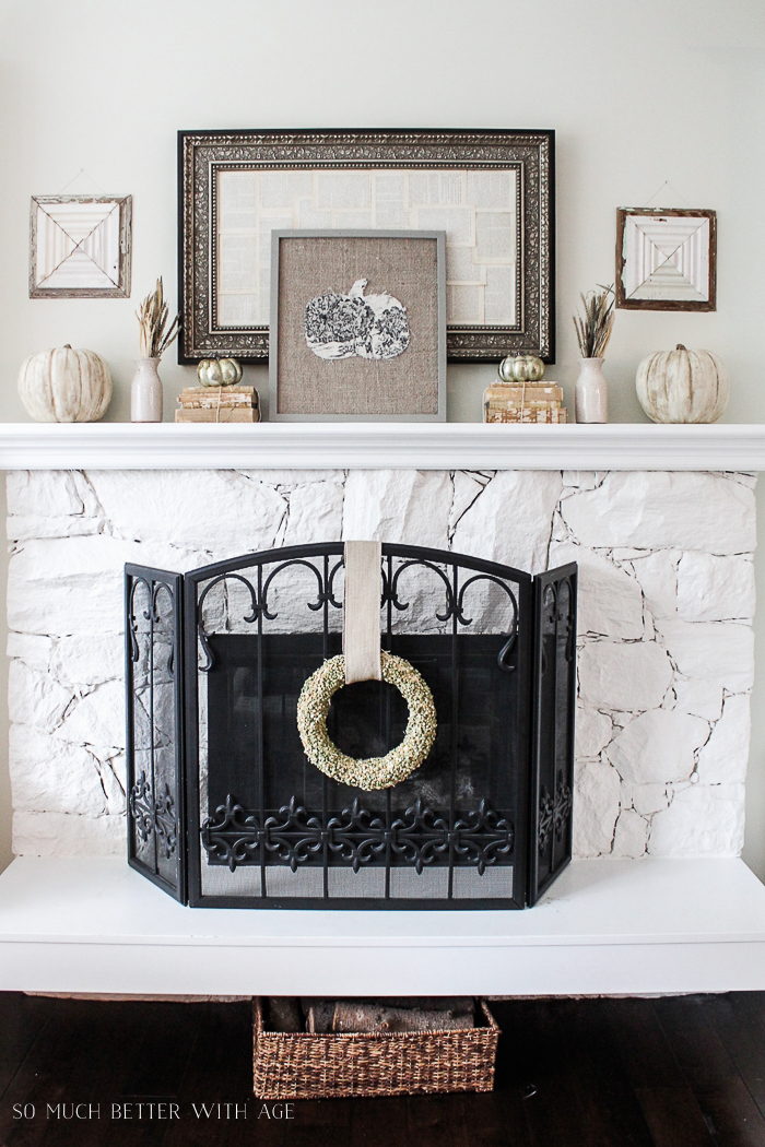 Split pea wreath hanging on the fireplace with pumpkin picture on the mantel.