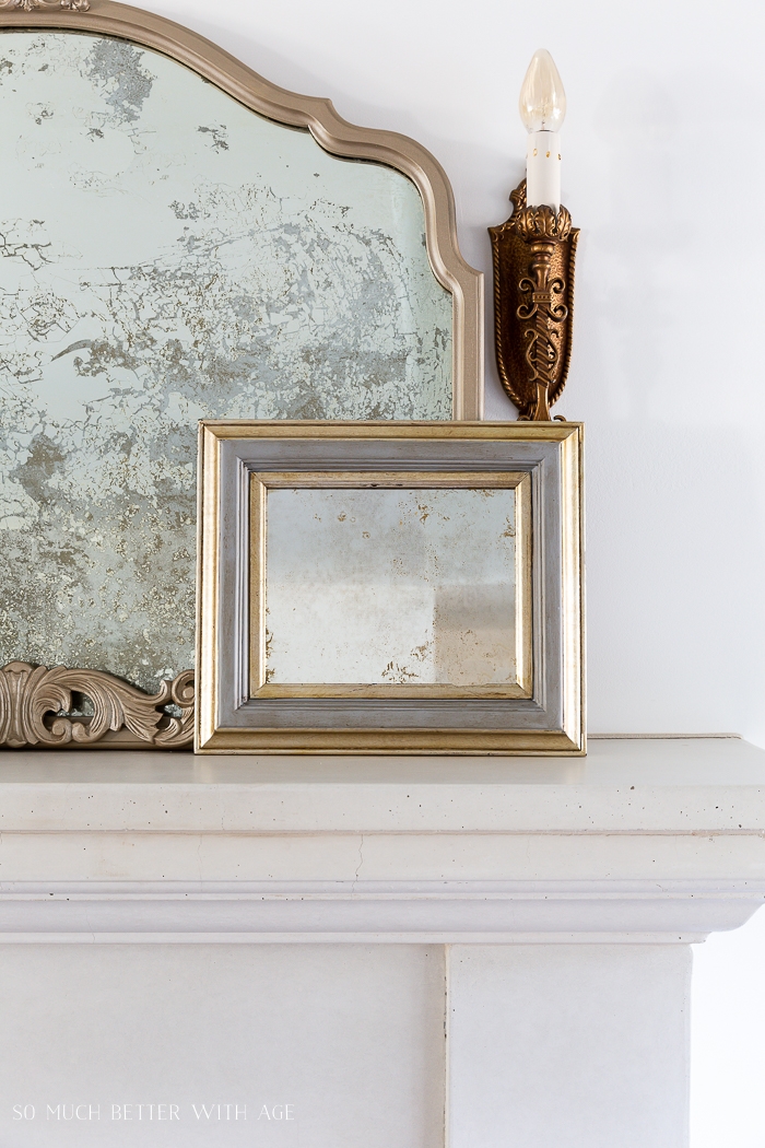 Antiqued mirrors with gold frames leaning on fireplace. 