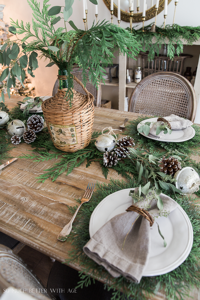 A French wicker jug with eucalyptus and evergreen in it, as a centrepiece in the middle of the table.