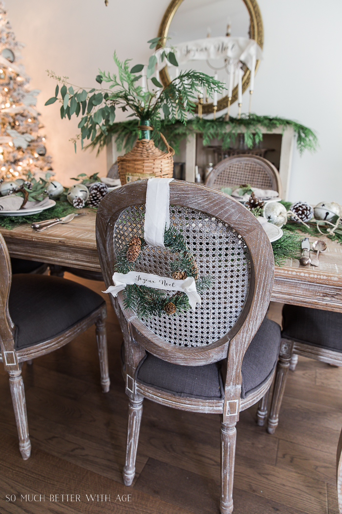 Dining room wooden chairs with evergreen wreaths hanging on the back.