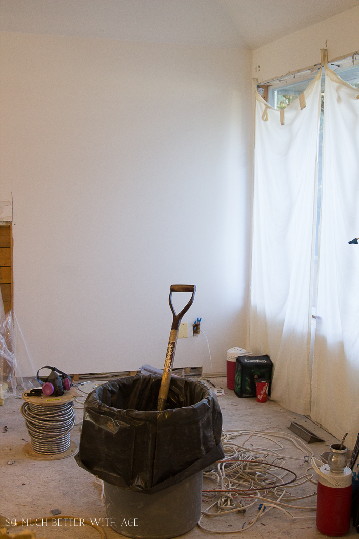 The garbage can with a shovel and wires in the living room during renovation.