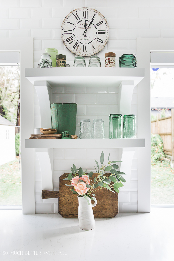 Green glass and pink flowers in the kitchen.