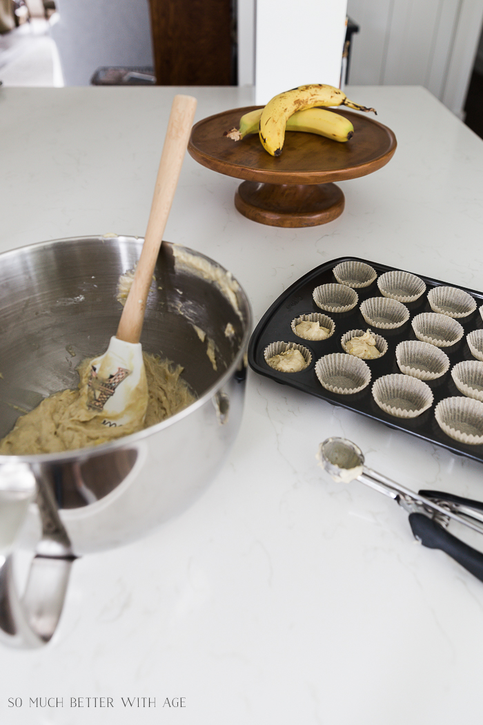 The banana muffin mix in a mixing bowl and mini muffin tin.