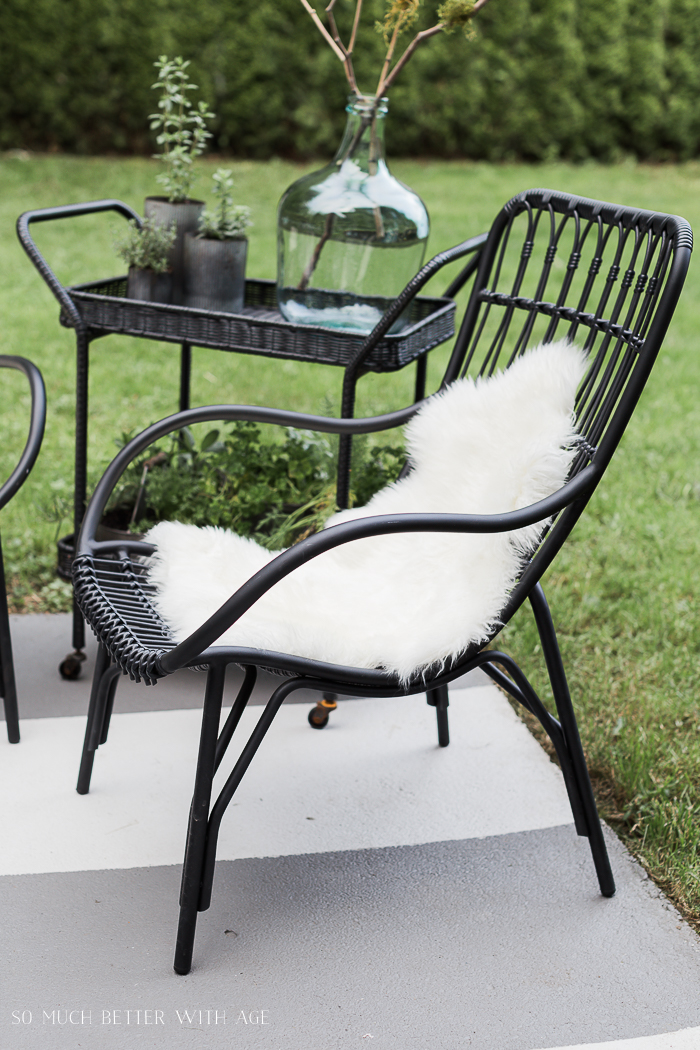 A metal outdoor chair with faux white fur on it.