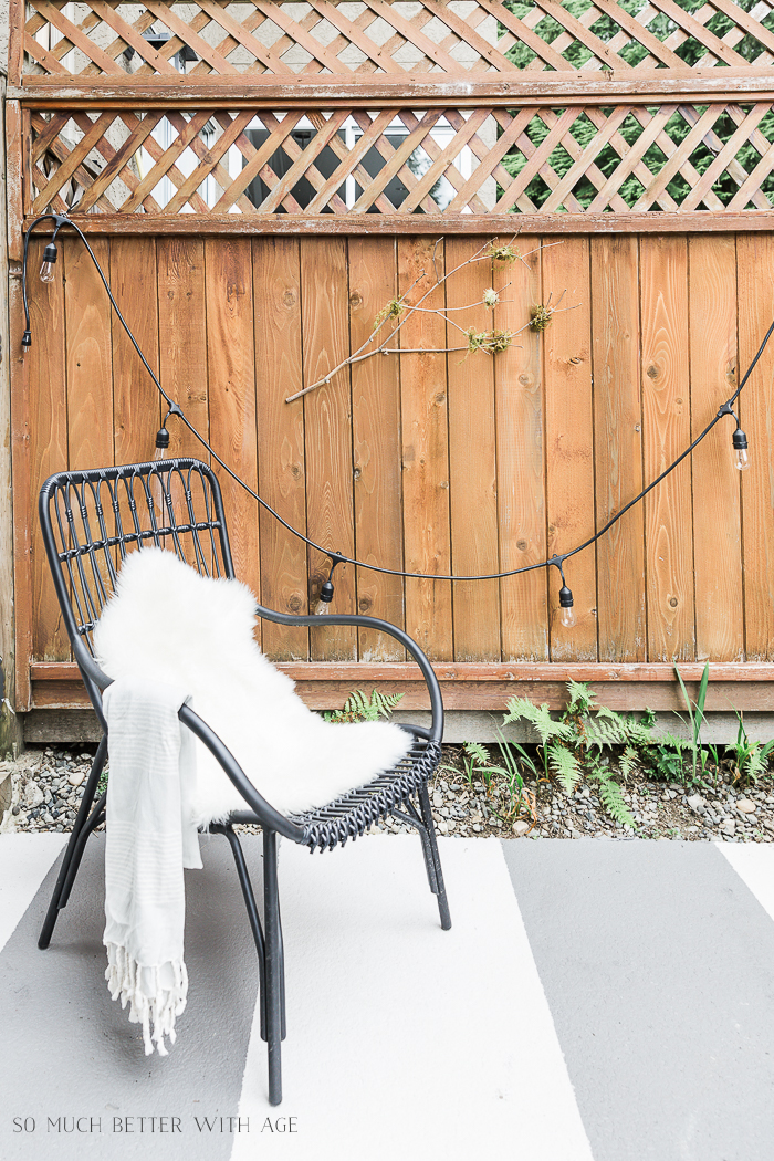 A striped outdoor painted patio with a chair with a white faux fur on it.