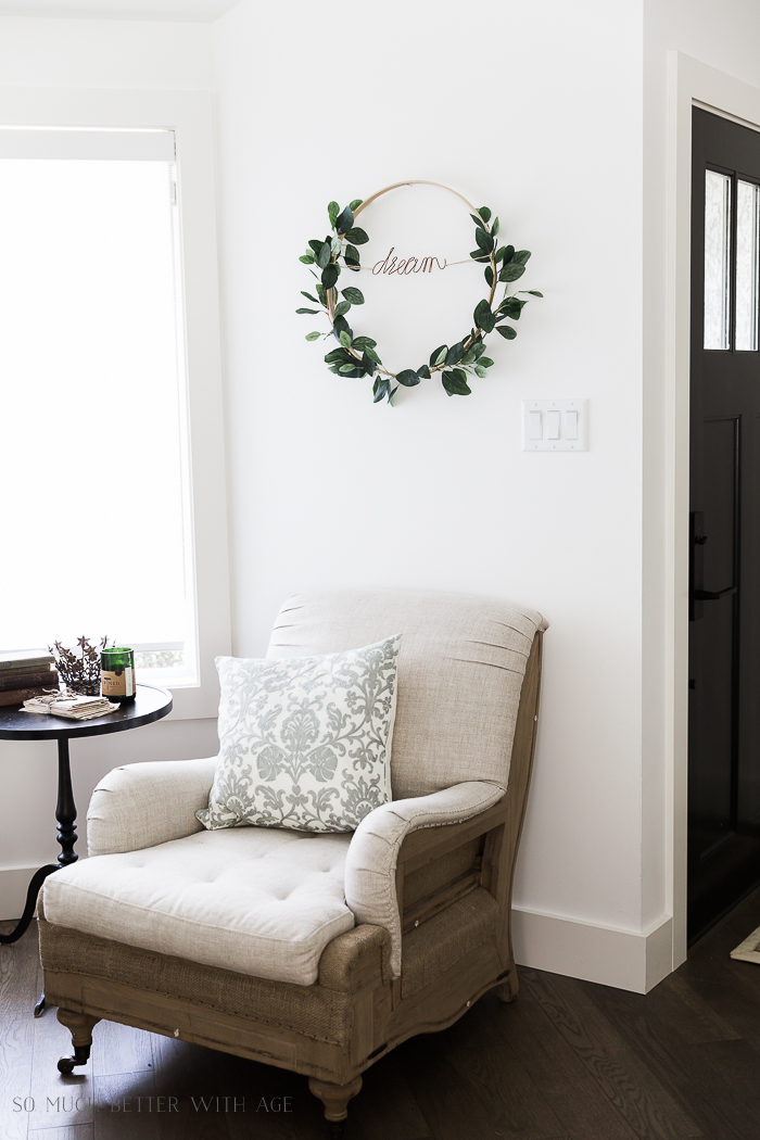 Summer Greenery Hoop Wreath on the wall above a chair.