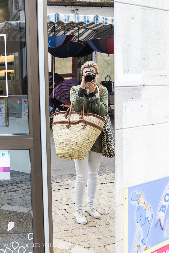Taking a photo in a mirror in the marketplace with umbrellas behind Jamie.