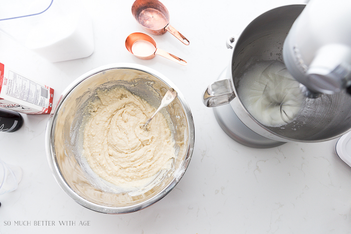 Stand up mixer with eggs in it and mixing bowl with flower dough mixture.