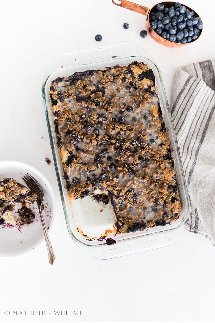 Blueberry streusel crumb cake with a half eaten piece on a plate and a tea towel beside it.