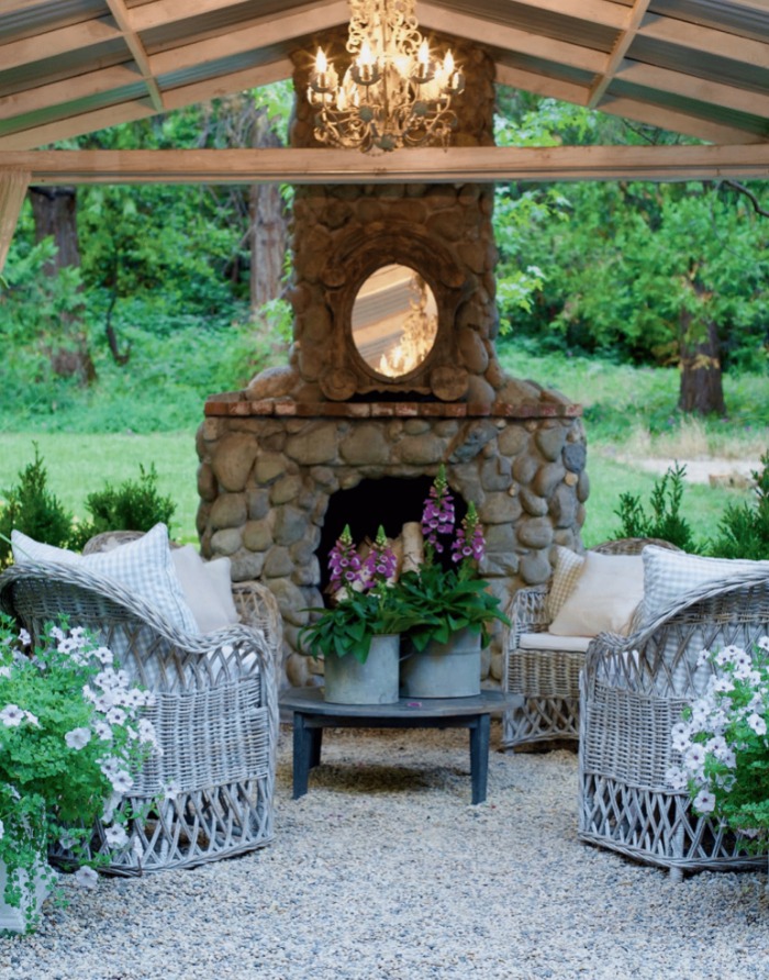 An outdoor fireplace with a small mirror and chandelier.