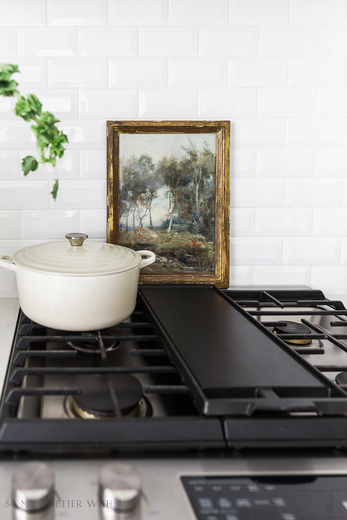 Oil painting in the kitchen behind the stove depicting a nature scene.